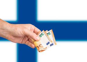 Hand with Euro banknotes over flag of Finland