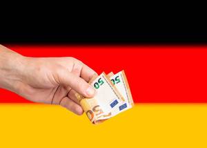 Hand with Euro banknotes over flag of Germany