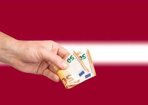 Hand with Euro banknotes over flag of Latvia