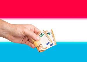 Hand with Euro banknotes over flag of Luxembourg
