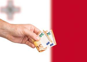 Hand with Euro banknotes over flag of Malta