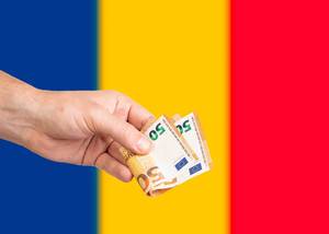 Hand with Euro banknotes over flag of Romania