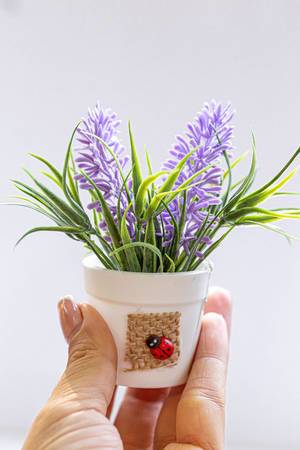 Hand with white bucket with purple flowers