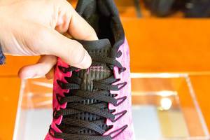 Hand zeigt Detail vom pink-schwarzen Laufschuh Nike Air Zoom Vomero 14 beim Chicago Marathon 2019 Expo