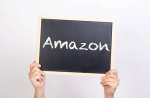 Hände halten eine Kreidetafel hoch, mit dem Wort "Amazon"