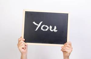 Hände halten eine Kreidetafel hoch, mit dem Wort "You" - Du