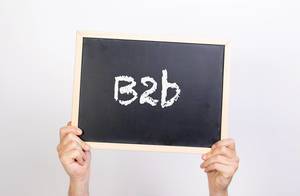 Hände halten eine Kreidetafel hoch, mit der Abkürzung "B2b" (Business to Business) -  Geschäftsbezeichnung zwischen zwei Unternehmen