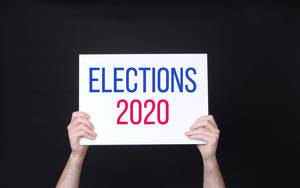 Hands holding board with Elections 2020 text against black background.jpg