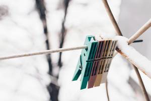 Hanging clothespins on snowy background.