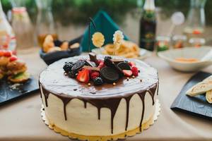 Hausgemachter weißer Geburtstagskuchen mit Schokoladenglasur und Beeren oben drauf