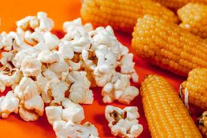 Heads of corn and popcorn on orange background