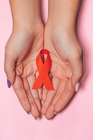 Healthcare and medicine concept - female hands with red AIDS awareness ribbon on pink background (Flip 2019)