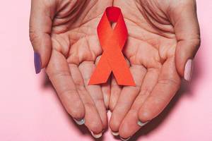 Healthcare, people, symbolic and medicine concept - close up of woman hands holding red AIDS awareness ribbon (Flip 2019)