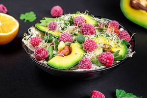 Healthy diet. Salad with raspberries and vegetables on a dark background