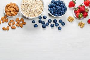 Healthy food background with fresh berries, almonds and oatmeal