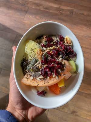 Healthy lunch with fruit such as melon and pineapple, sunflower seeds, cherries and walnuts in a white bowl
