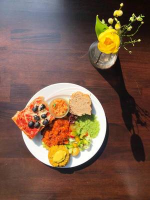 Healthy lunch with olive pizza, couscous-curry, white bread and fruit salad on a white plate