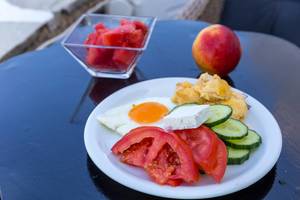 Healthy snack with fresh tomatoes, cucumber, feta cheese, scrambled eggs and watermelon