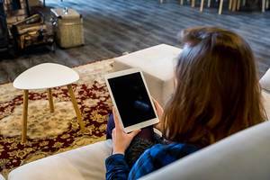 Heimarbeit: Frau arbeitet mit einem Tablet vom Wohnzimmer aus