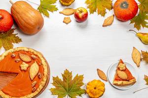 Herbst Rahmen mit Blättern, Kürbiskuchen, Äpfeln, reifen Kürbissen und hausgemachten Keksen auf weißem Holzhintergrund