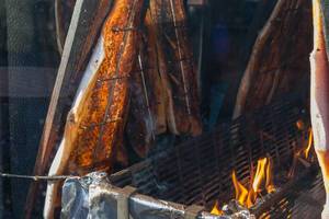 Herstellung von Flammlachs - Fischhälften hängen über offenem Feuer am Neumarkt in Köln