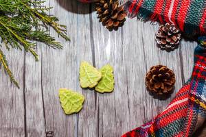Hintergrund passend zur Festzeit mit Keksen in Weihnachtsbaum-Form, Kiefernzapfen und Ast