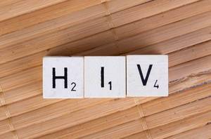 HIV mit Scrabblesteinen auf einer Holzoberfläche geschrieben