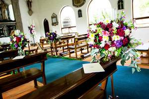 Hochzeitsdekorationen mit Blumen auf den Bänken in einer Kirche