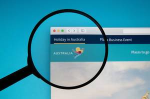 Holiday in Australia website on a computer screen with a magnifying glass