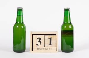 Holzkalender zeigt den 31. Dezember zwischen zwei Bierflaschen vor weißem Hintergrund