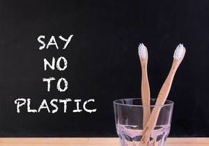 Holzzahnbürsten im Glas, neben dem Text "Say No To Plastic" / Sag nein zu Plastik