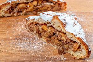 Homemade apple strudel with apples, nuts and powdered sugar on wooden background (Flip 2019)