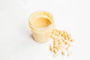 Homemade peanut butter in glass jar isolated on white background