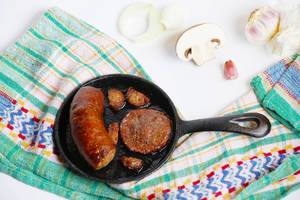 Homemade sausage frying in a small pan