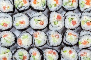 Homemade sliced Maki rolls with salmon, avocado and cucumber. Top view