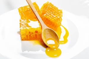 Honeycomb with wooden honey spoon and honey