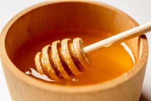 Honeypot -  clear honey in a bright wooden pot close up