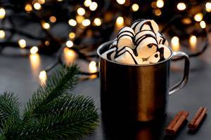 Hot chocolate with marshmallows on a Christmas background with bokeh and Christmas tree branches