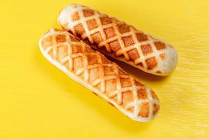 Hot dogs in waffles on a yellow background, top view (Flip 2020)