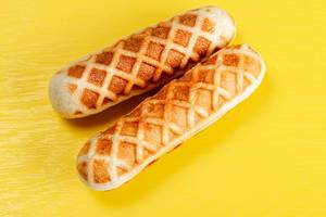 Hot dogs in waffles on a yellow background, top view
