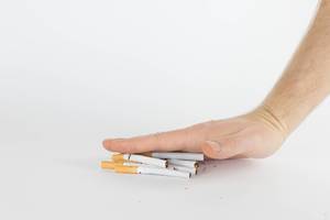 Human hands breaking stack of cigarettes