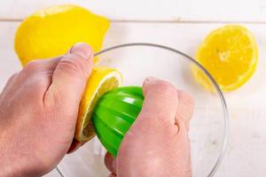 Human hands squeeze the juice from half of lemon (Flip 2019)