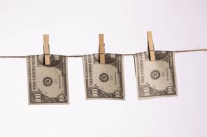 Hundred dollar bills bent in half hanging on clothes line