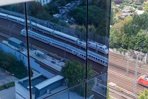 ICE-Zug fährt auf den Gleisen zum Bahnhof Spandau und spiegelt sich in der Glasfassade / Fensterfassade und Hauswand des Spiegelturms in Berlin