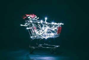 Im Dunkeln stehender Einkaufswagen weihnachtlich beleuchtet durch die darin liegenden Lichterketten