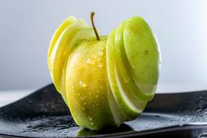 In Scheiben geschnittener grüner Apfel mit Wassertropfen als Dessert angerichtet