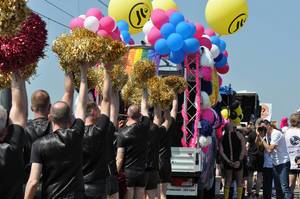 In schwarz gekleidete Männer mit bunten Pompons bei der Cologne Pride Demo