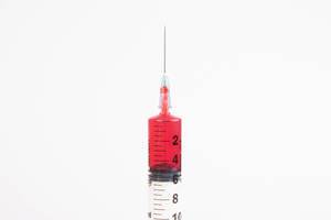 Injektionsnadel und Blut in einer Spritze, vor weißem Hintergrund