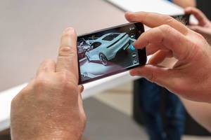 Instagramer auf der Autoaustellung: Mann macht ein Bild mit dem Smartphone vom Elektro-Sportwagen Taycan Turbo S von Porsche
