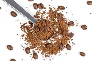 Instant coffee and whole coffee beans on a white background with an iron spoon